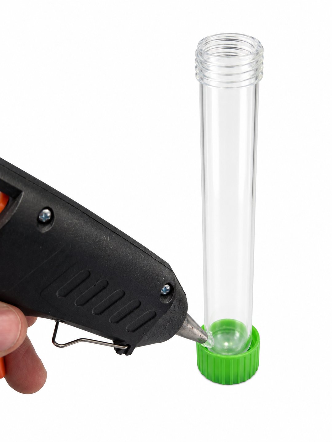 Hot glue gun applying glue where the round end of the clear test tube sits inside the upside-down green cap