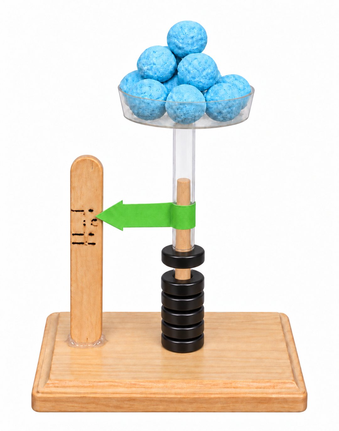 Finished magnetic spring scale: a clear tube rests on the floating black ring magnets, a petri dish tray with foam balls sits on top of the tube, and a green paper arrow on the tube points at pen marks on a craft stick glued to the base